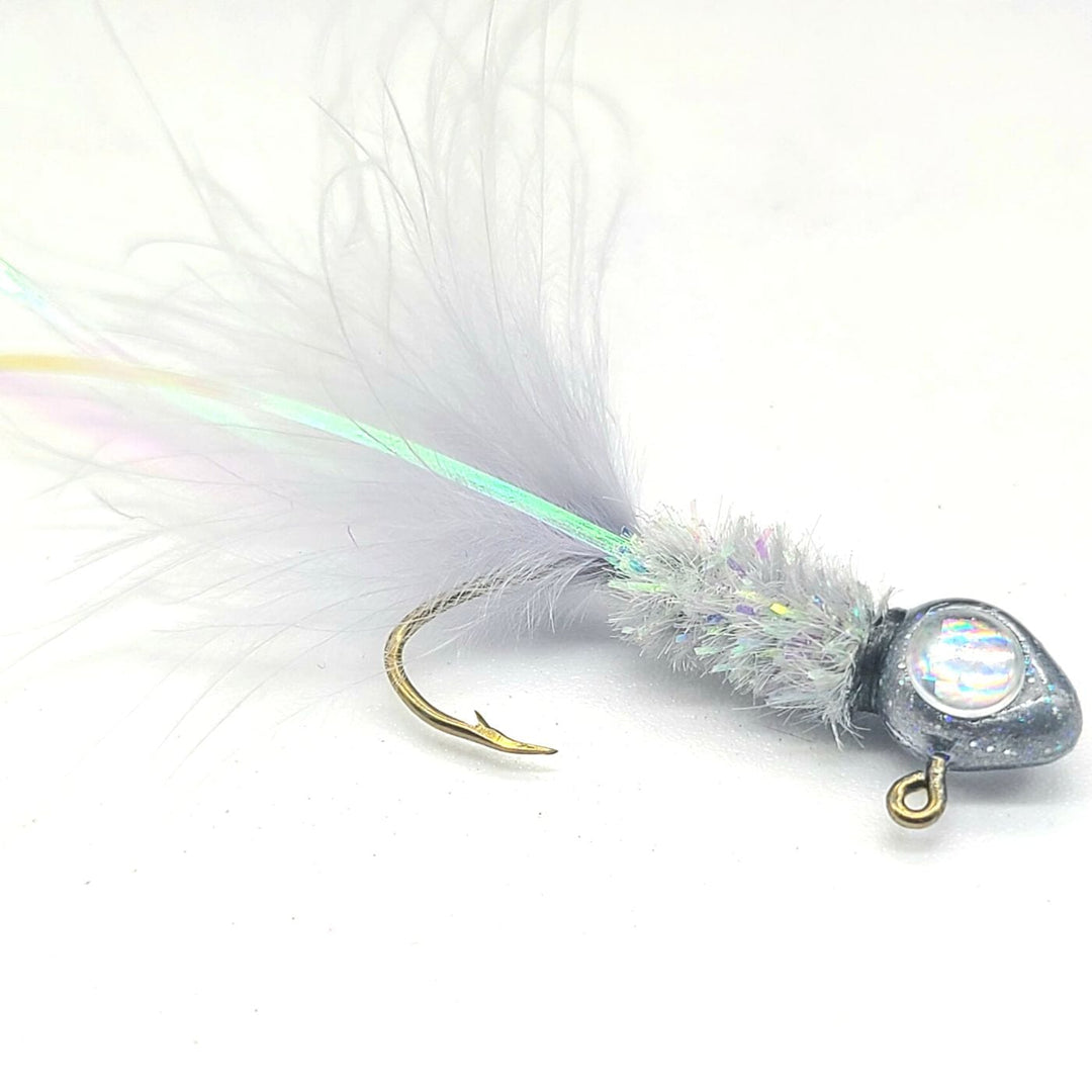 "Hand tied crappie jig with a light gray feather tail, an iridescent body made of synthetic material, and a round silver jig head. This crappie lure features a sickle hook, designed to attract fish by mimicking the appearance and movement of prey in the water, making it an effective and visually appealing bait for crappie fishing. This fishing lure is hand tied by Ramble Tamble Tackle."